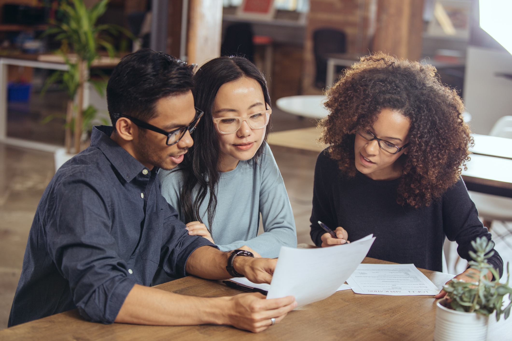 College students meeting with an agent in a cafe to discuss student loan refinancing options.