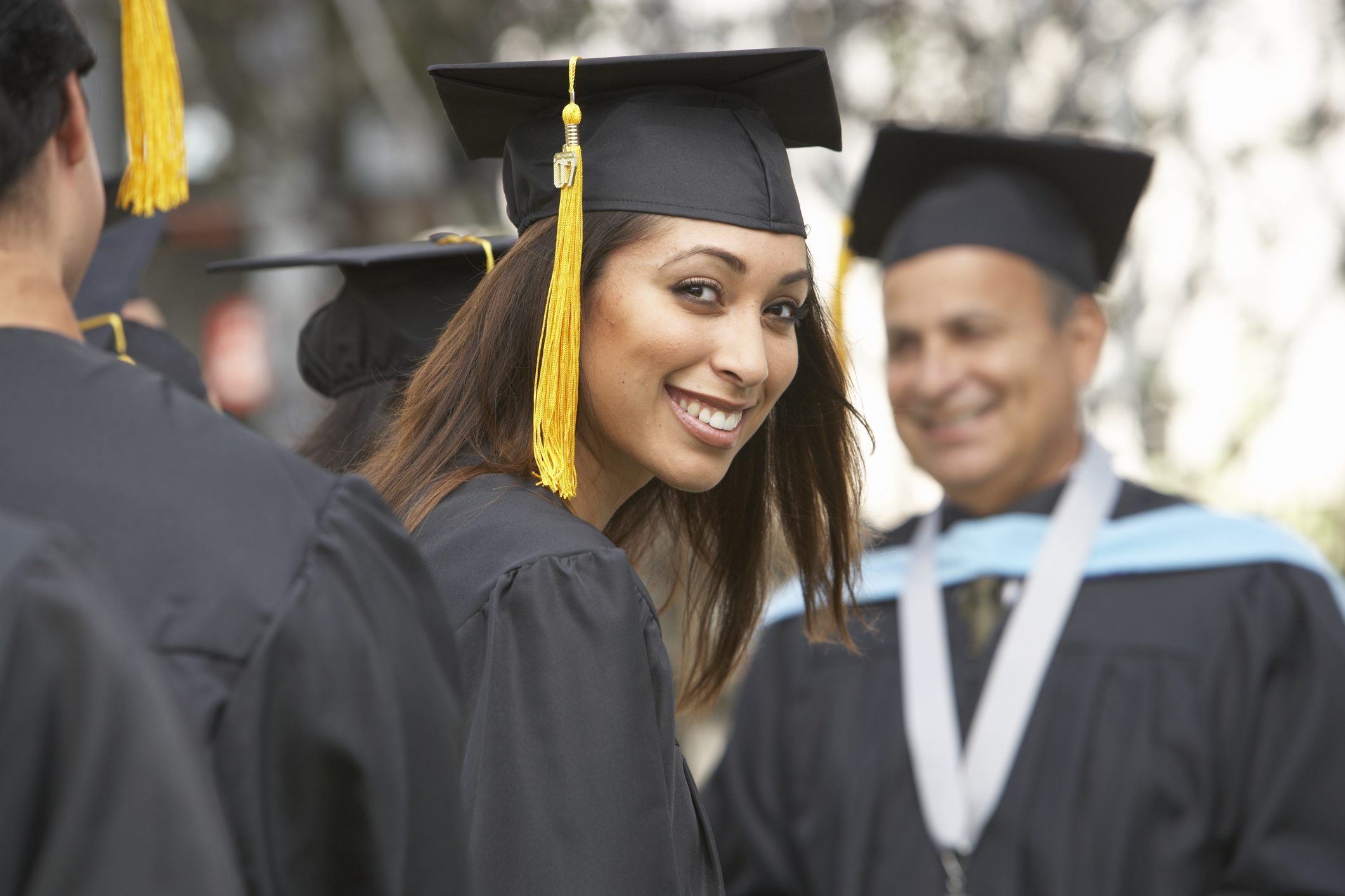 Adult college student smiling at her graduation ceremony.