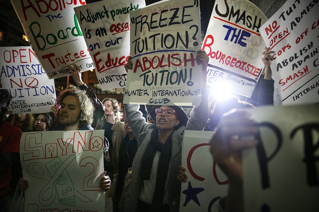 Students hold placards as they stage a demonstration to protest ballooning student loan debt and rally for tuition-free public colleges in New York.