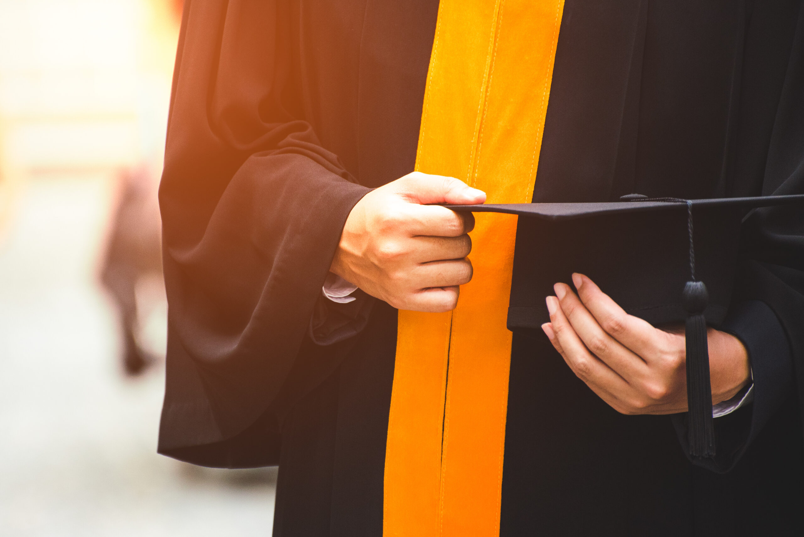 Close up of a graduate holding a graduation cap.