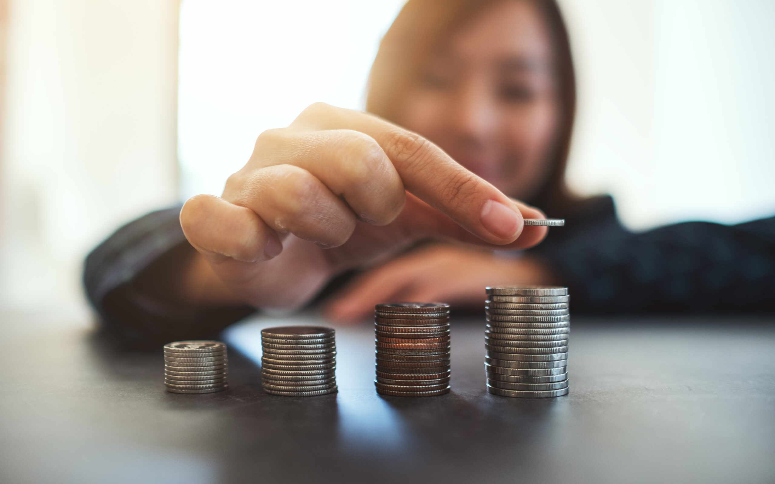 Businesswoman holding and stacking coins on the table