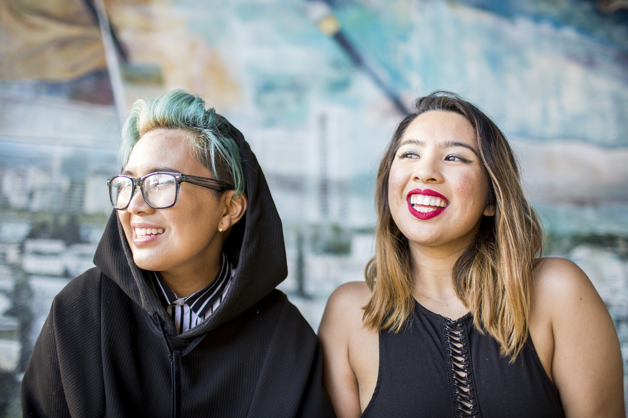 two friends smile off to the side of the camera.