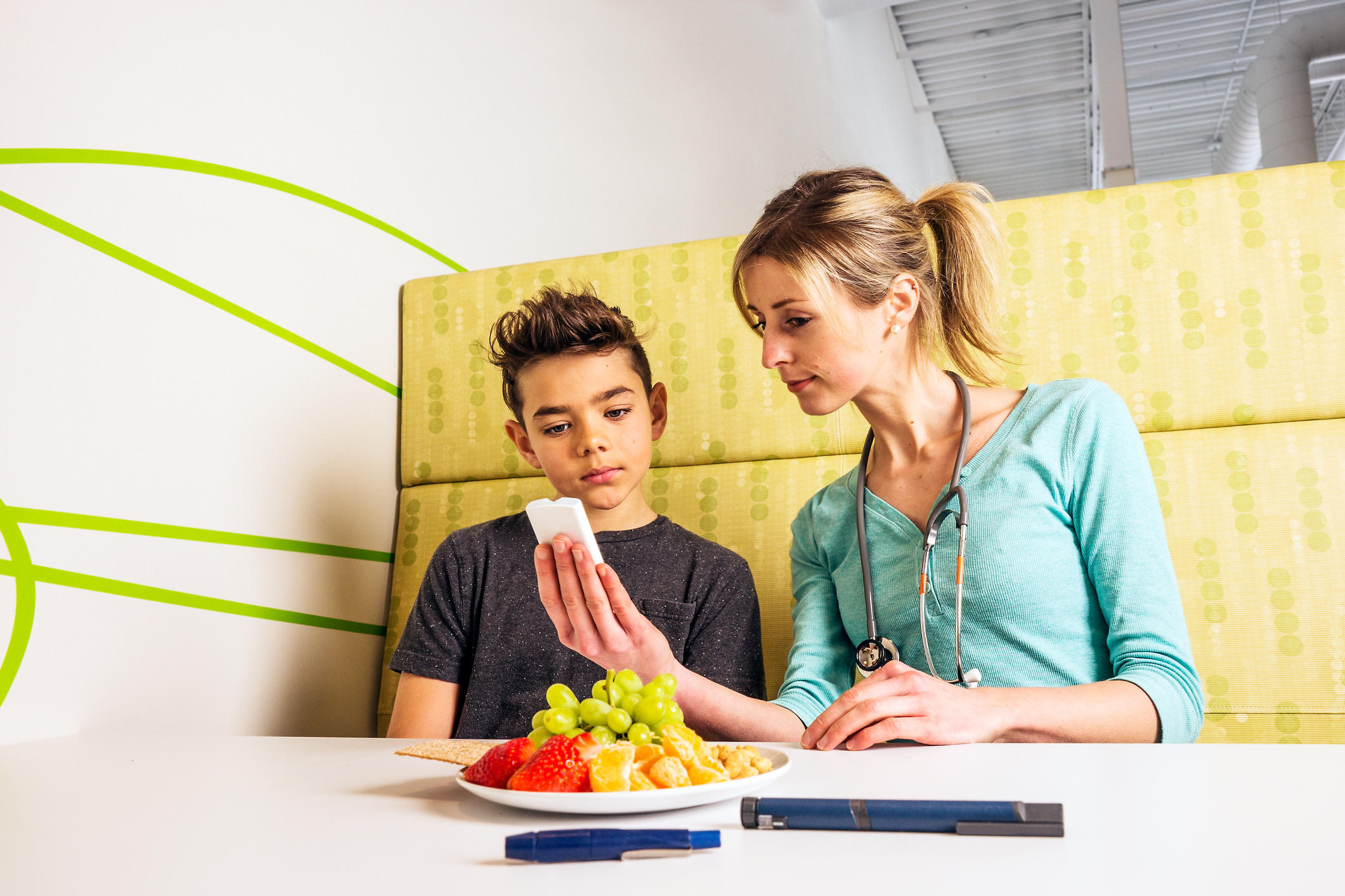 A diabetes health care professional with a young patient. The nutritionist, doctor or nurse is explaining how to manage and monitor blood glucose levels.