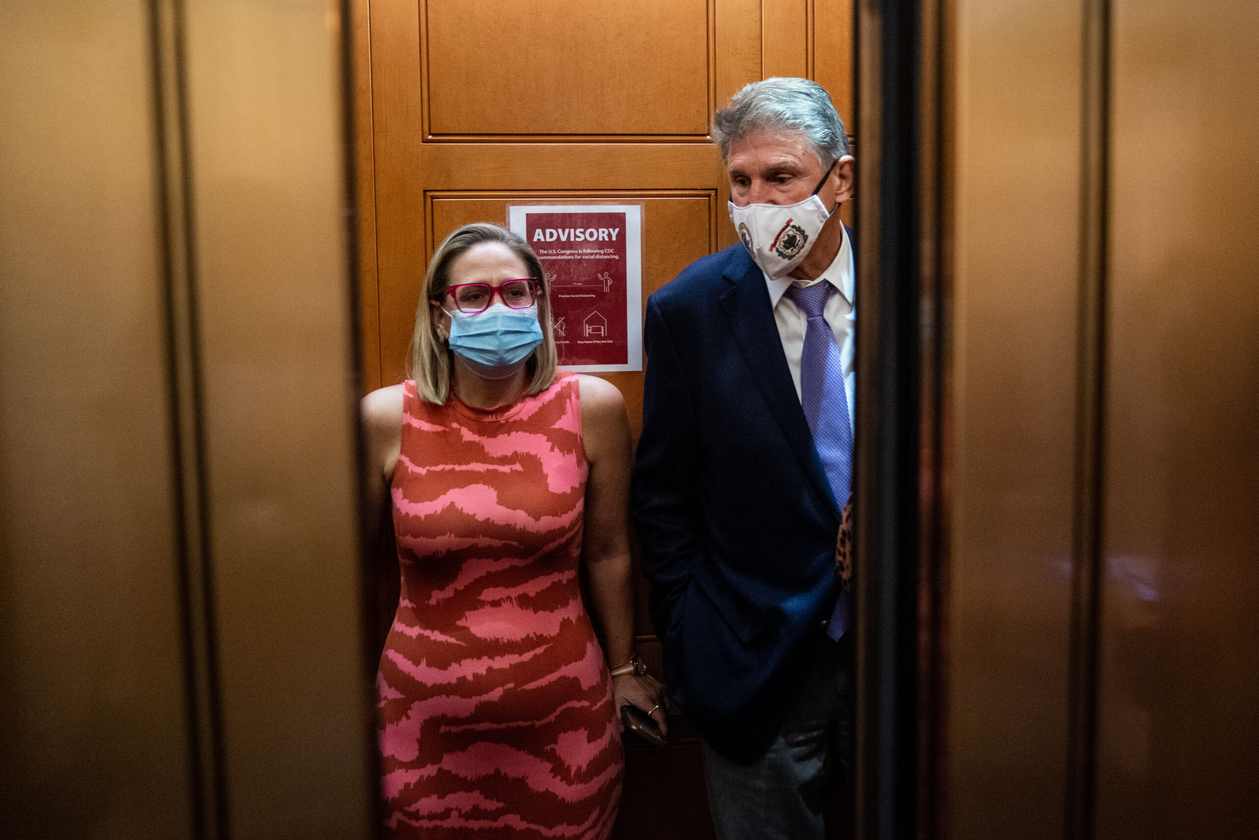 Sen. Kyrsten Sinema and Sen. Joe Manchin catch and an elevator to go to the Senate Chamber to vote