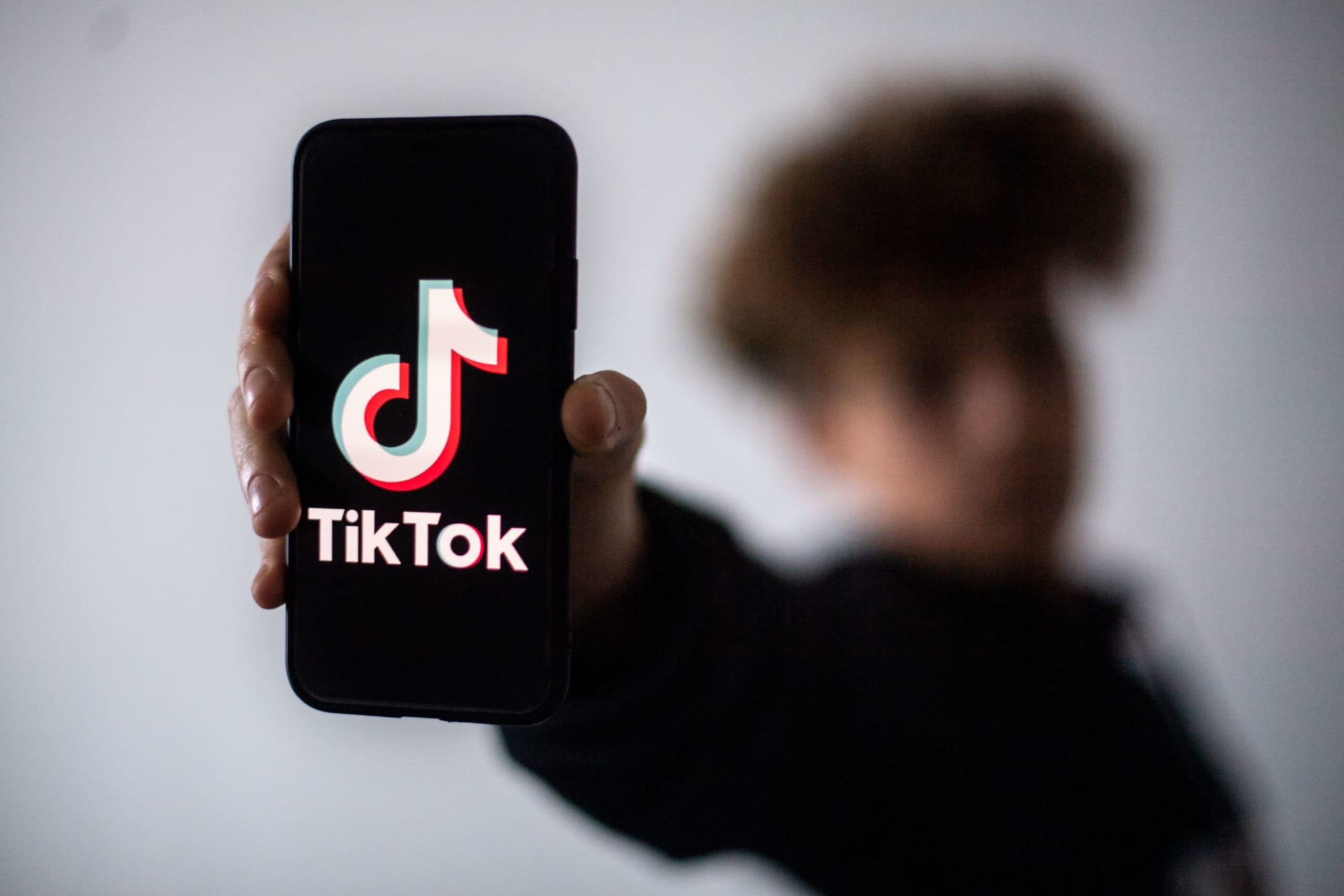 A teenager presents a smartphone with the logo of Chinese social network Tik Tok