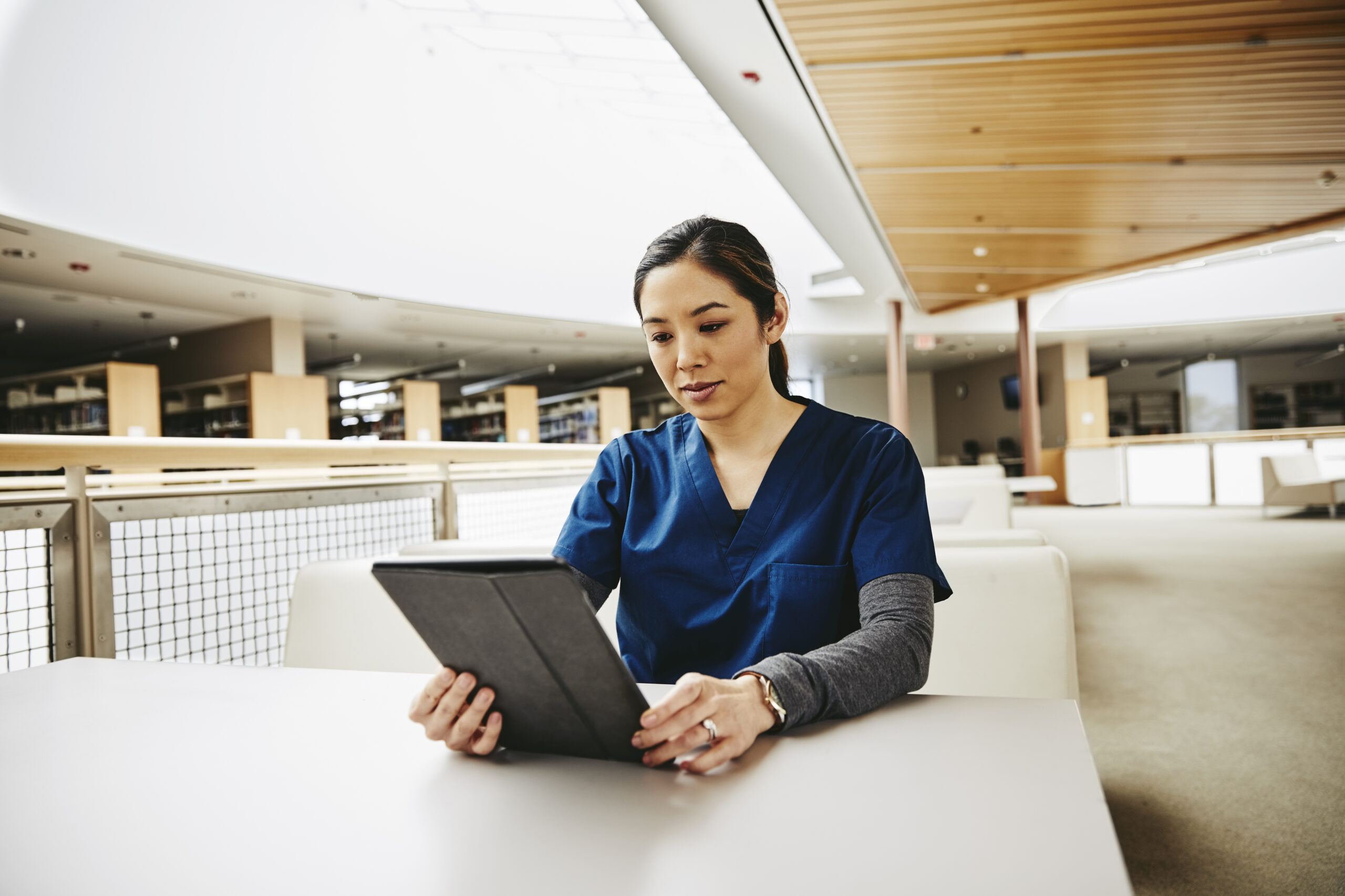 Female medical student using digital tablet at table in library