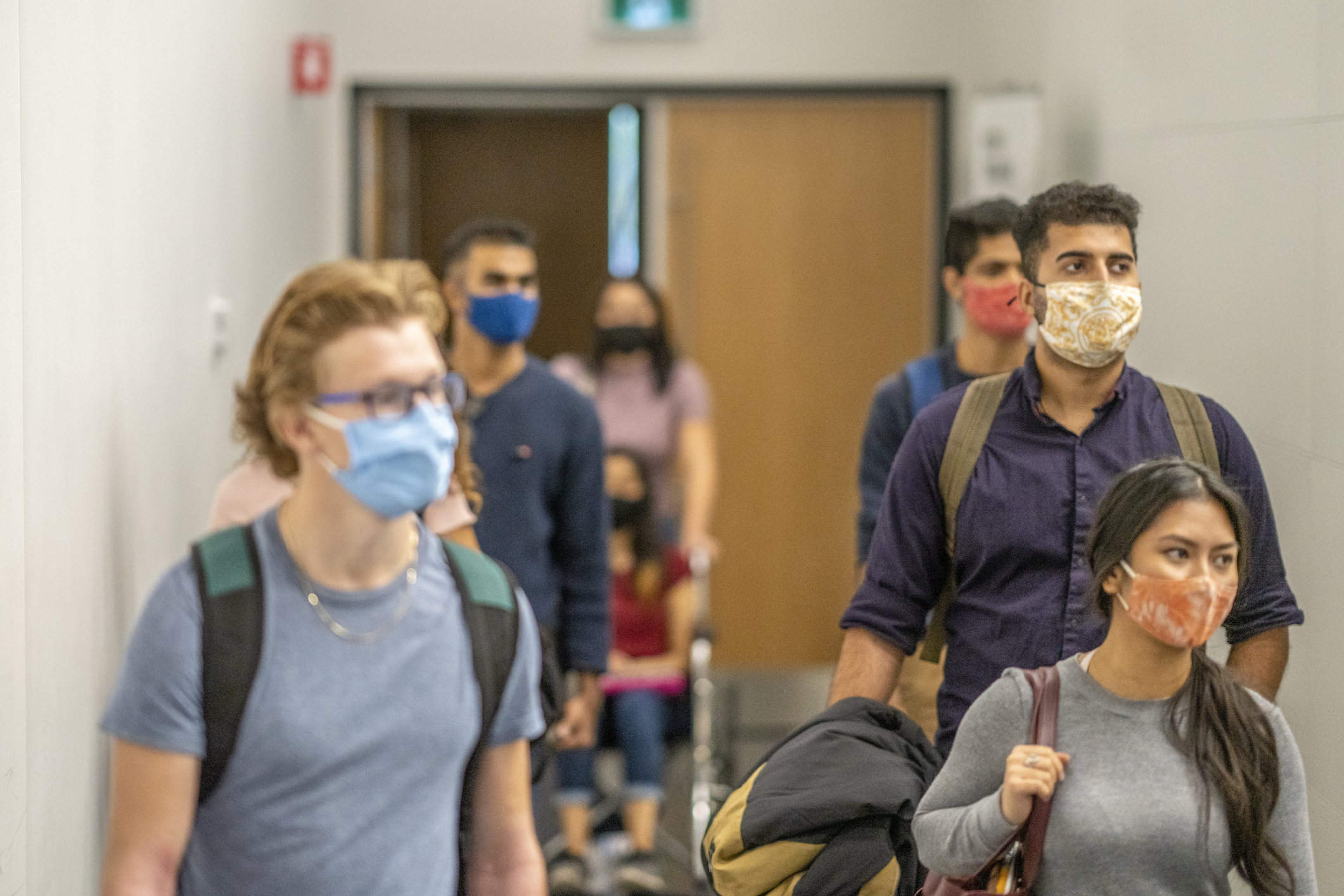 Colleges students filing into class while wearing protective face masks.