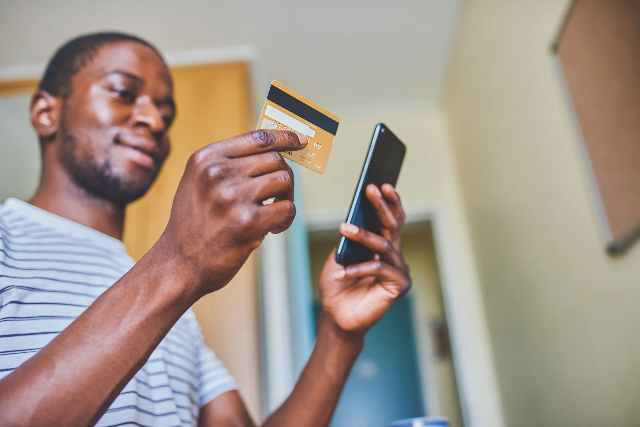 A college student holds a credit card in one hand and a smartphone in another.