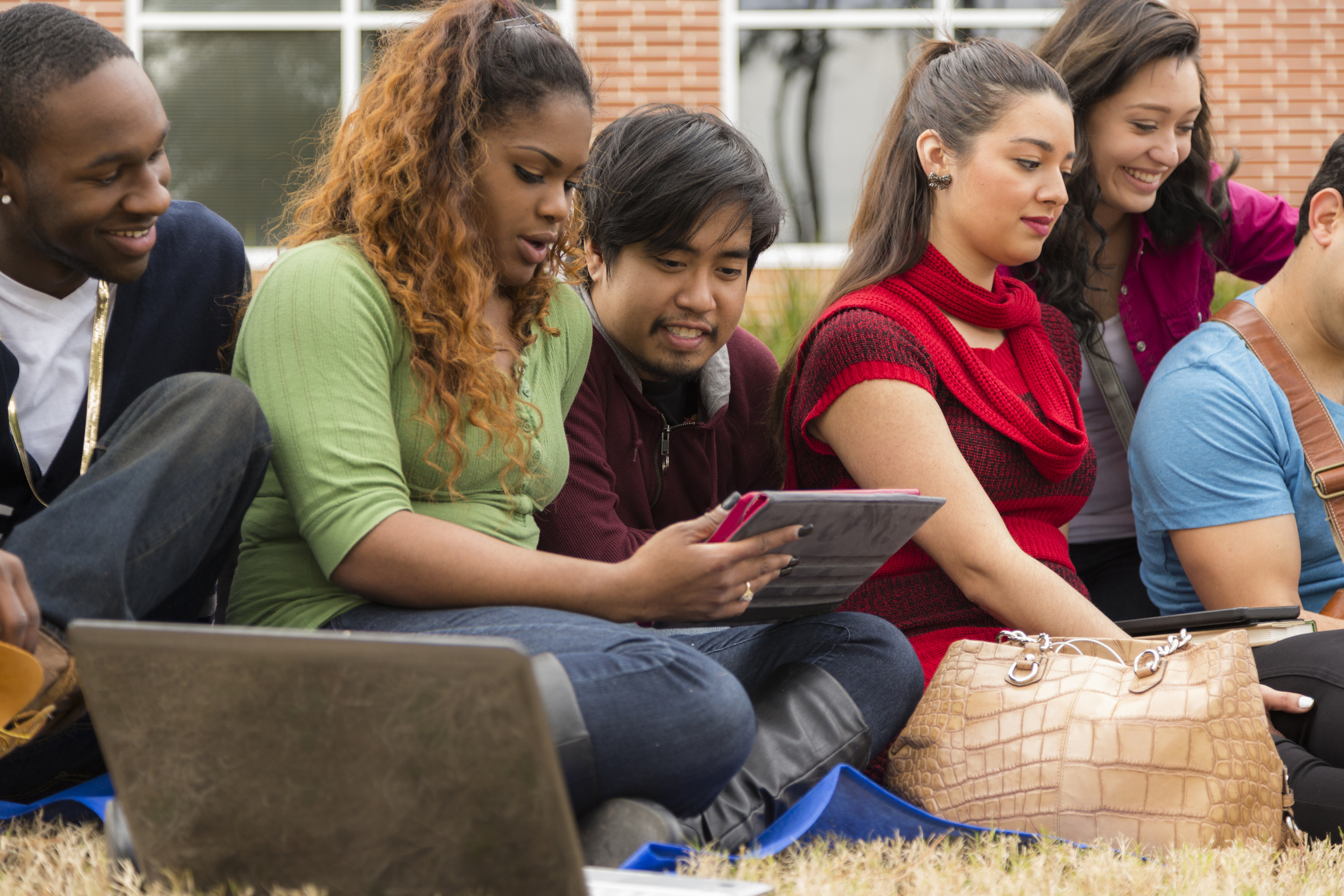 Group of multi-ethnic international college students hanging together outside on a campus square.