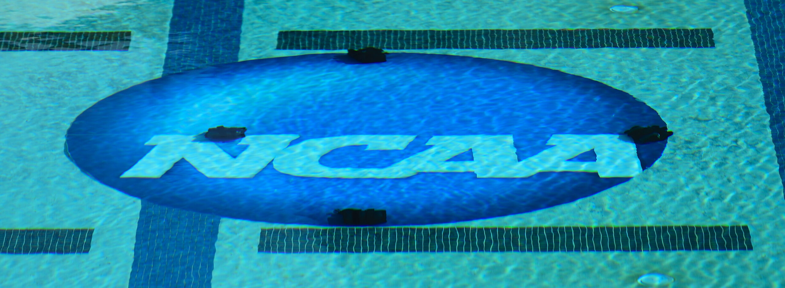 The NCAA Logo photographed from above. The logo is on the bottom of a collegiate swimming pool.