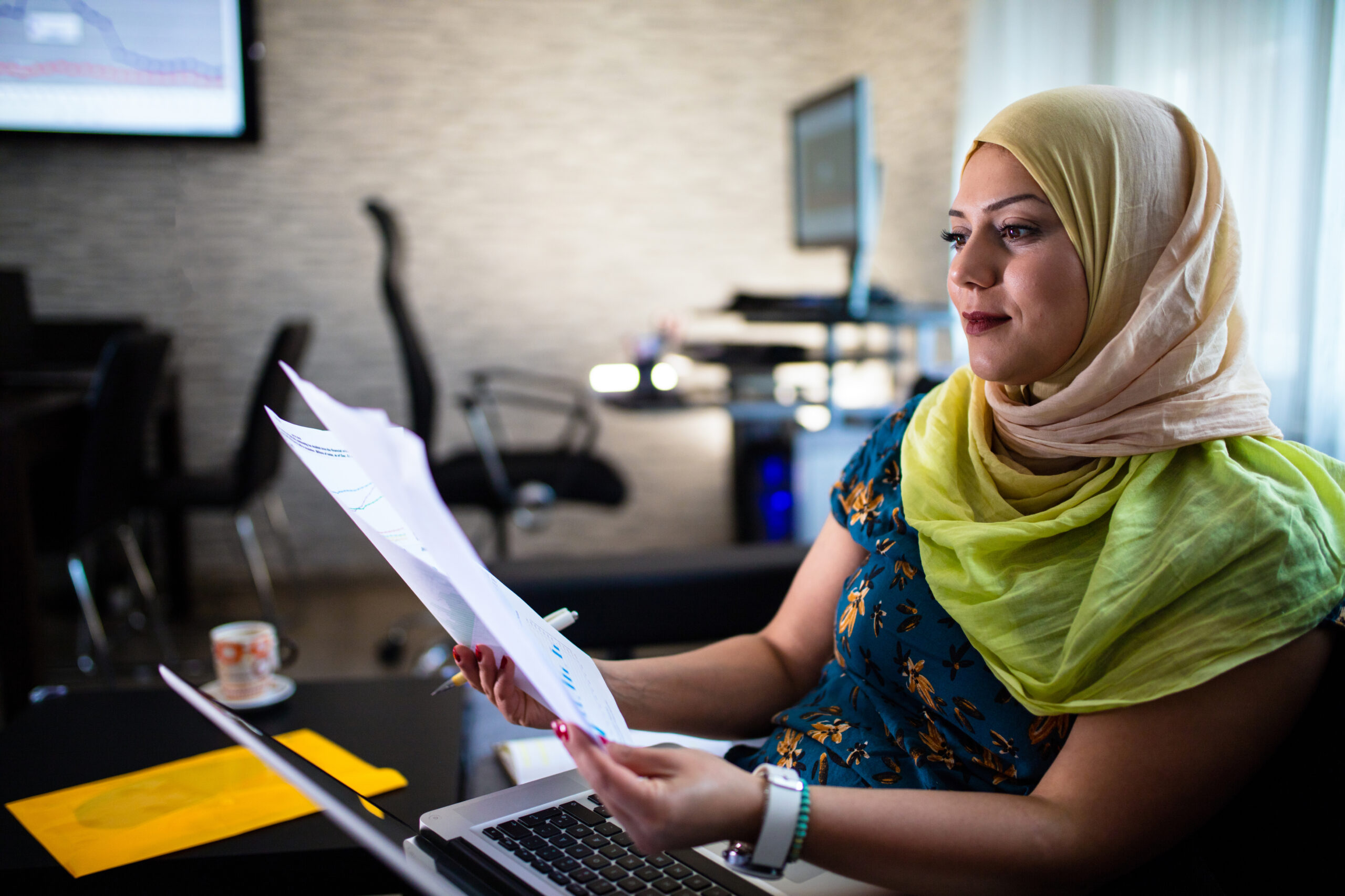 Muslim woman sitting at a desk looking over some documents