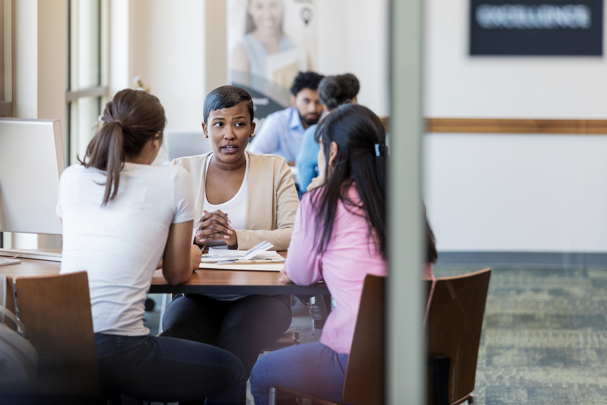 Mom and her college-aged daughter talk with a university financial aid employee about applying for a HEERF grant.