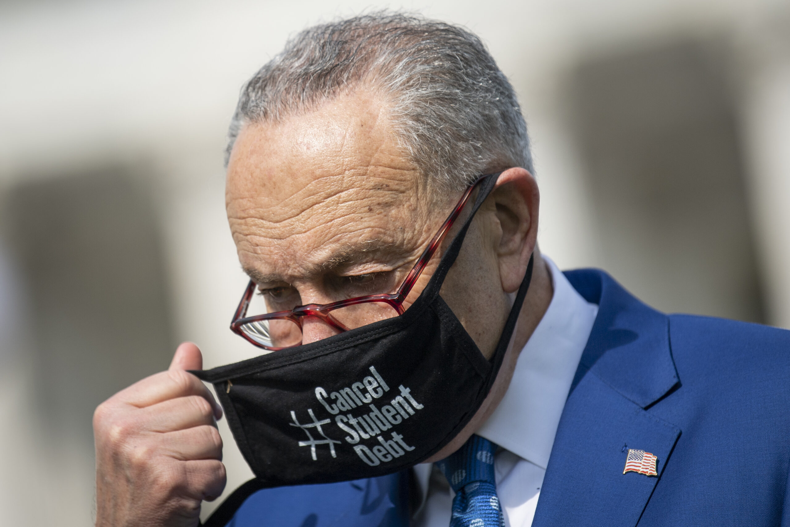 Picture of Chuck Schumer Putting on a face mask while at a press conference