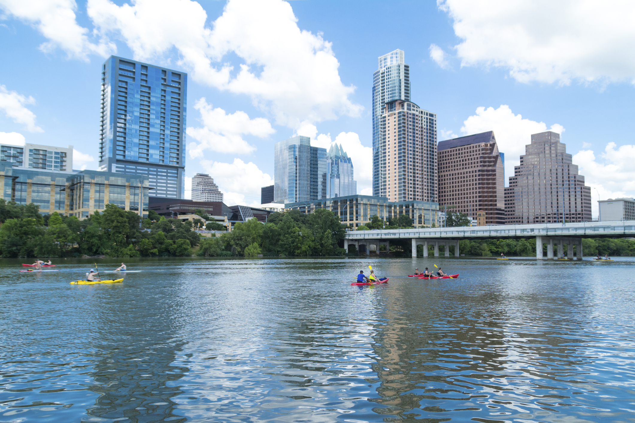 A distant view of people canoeing on Lady Bird Lake in Austin Texas with the Austin skyline in the background