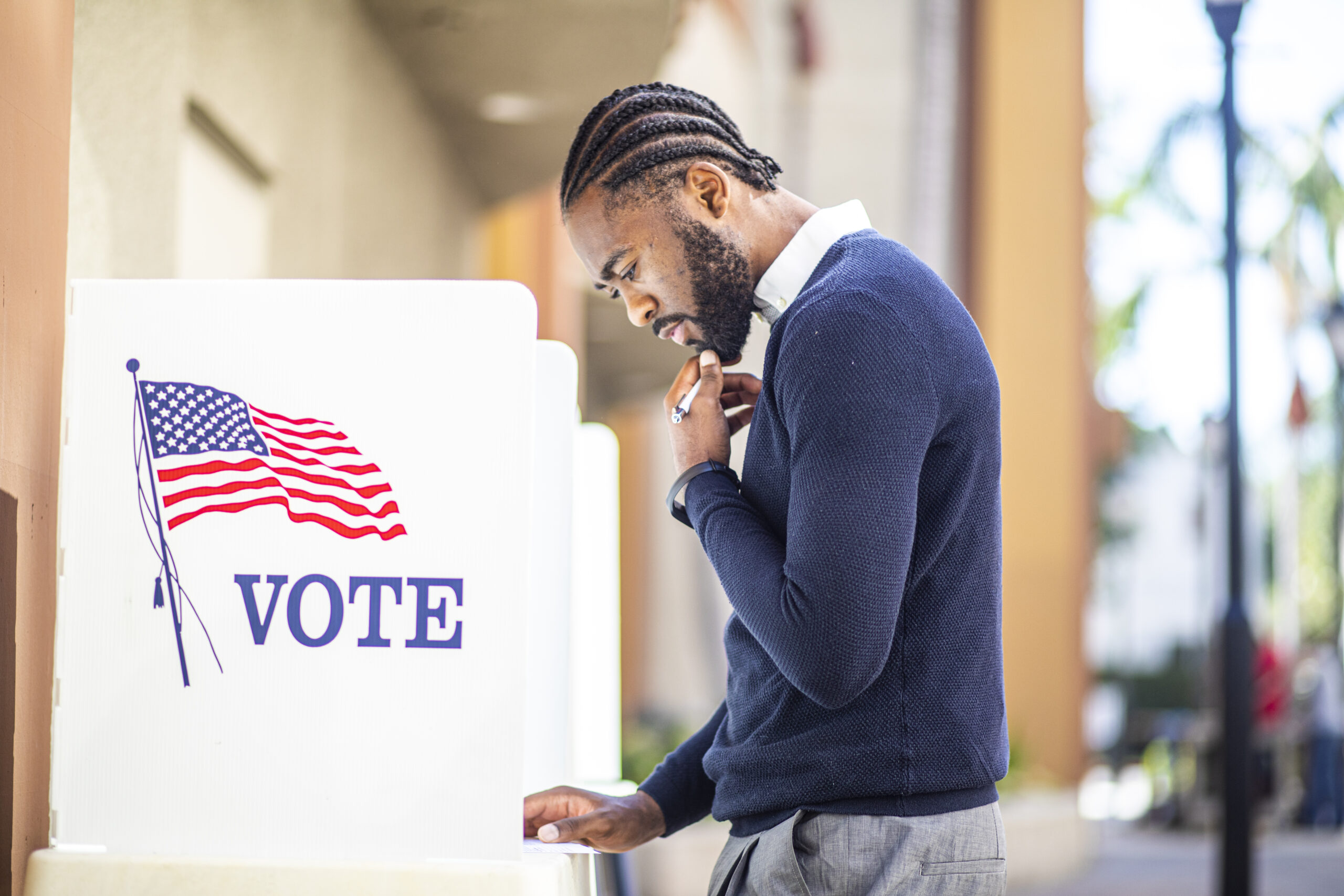 A millennial black man voting at a voting booth in an election.