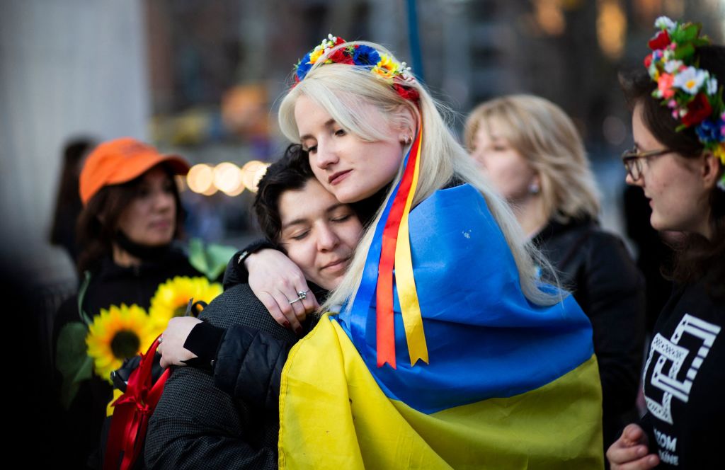 Women, wrapped in a Ukrainian flag, embrace during a flash mob protesting sexual abuse by Russian soldiers in Ukraine, at Washington Square Park in New York, April 8, 2022.