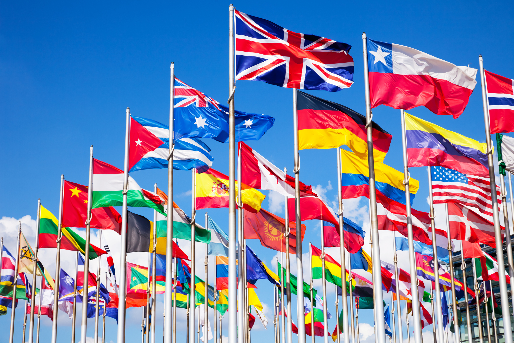 A series of flags from international countries sway in the wind in front of a college campus building. American colleges and universities are beginning to accept international students following enrollment declines during the COVID-19 pandemic.