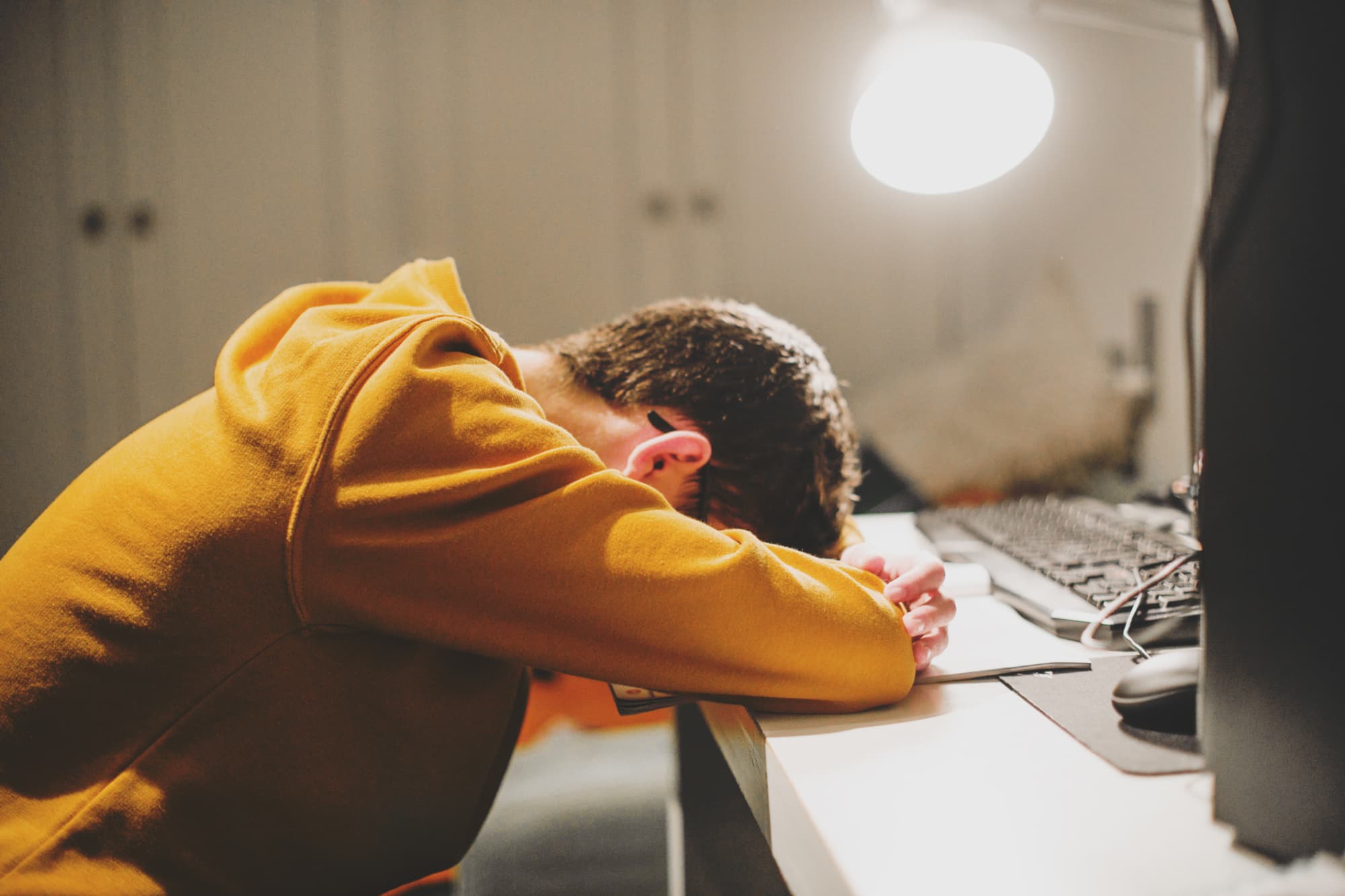 A stressed student laying there head down on their desk while working late at night