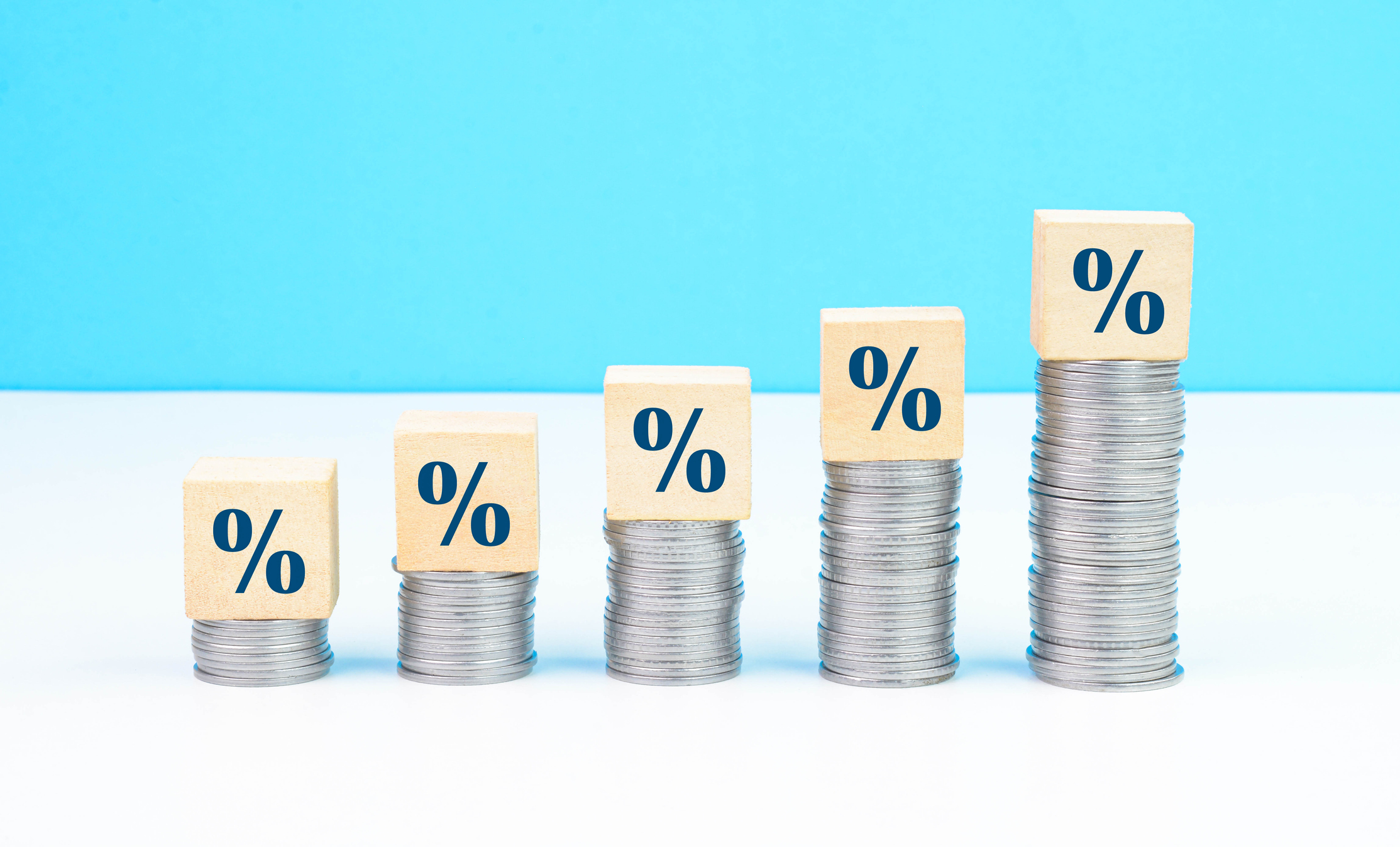 An illustration showing percentage signs above 5 coin stacks, with each stack increasing in value over time.