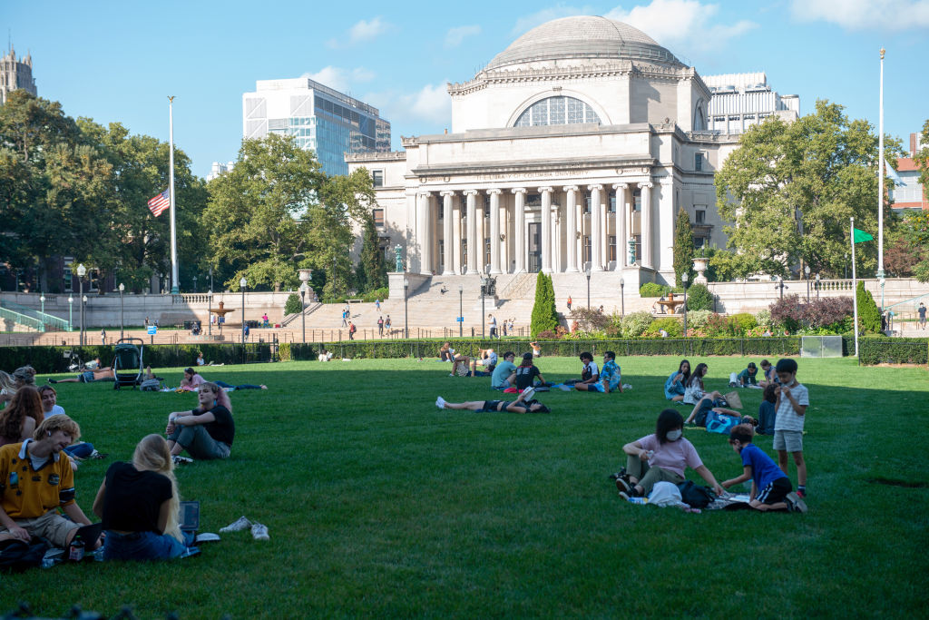 People sit on the grass at Columbia University in New York City. The university said it needs more time to reevaluate its data after a professor alleged it may have skewed numbers in previous years.