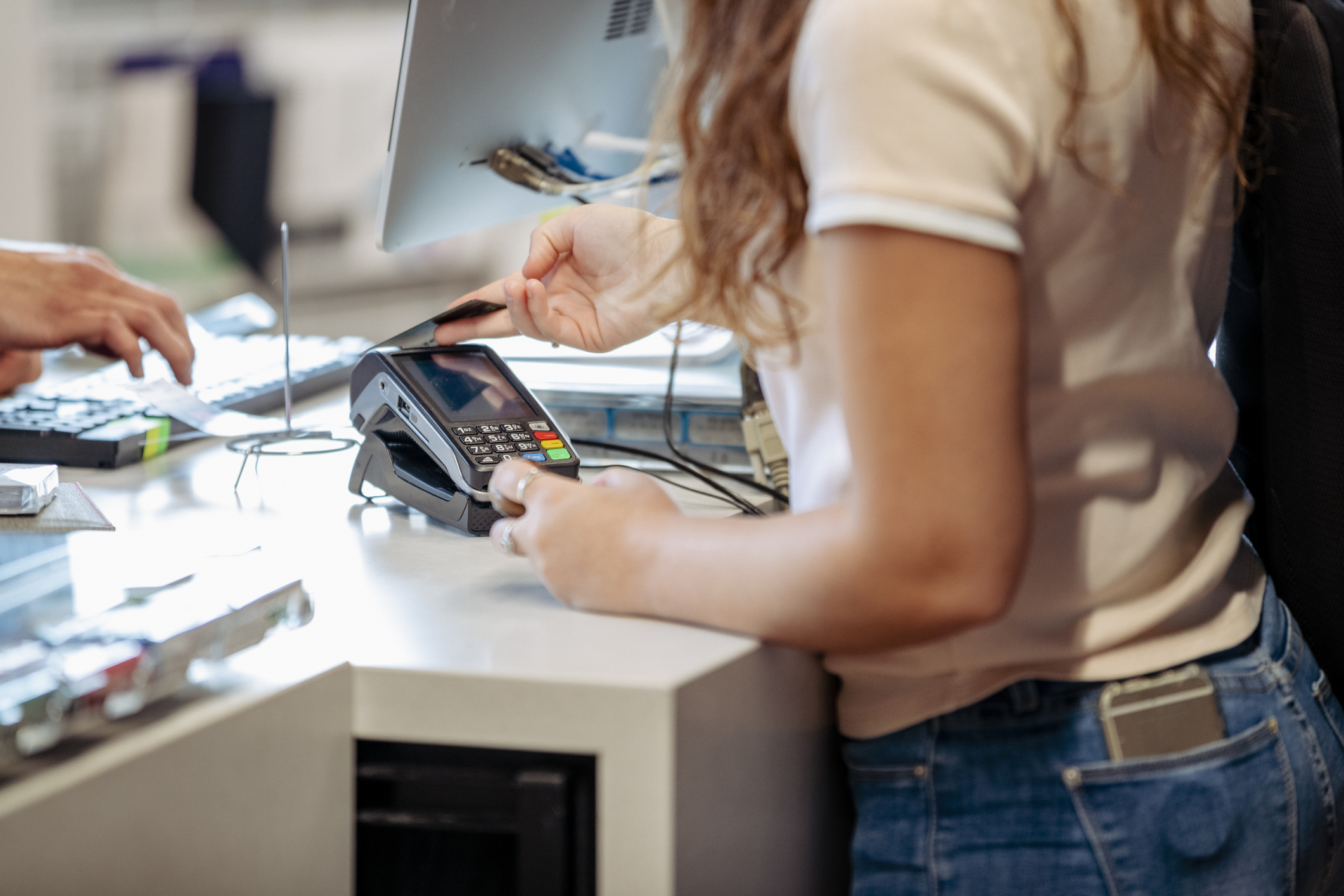 Female college student buying textbooks at a store on campus using her credit card.