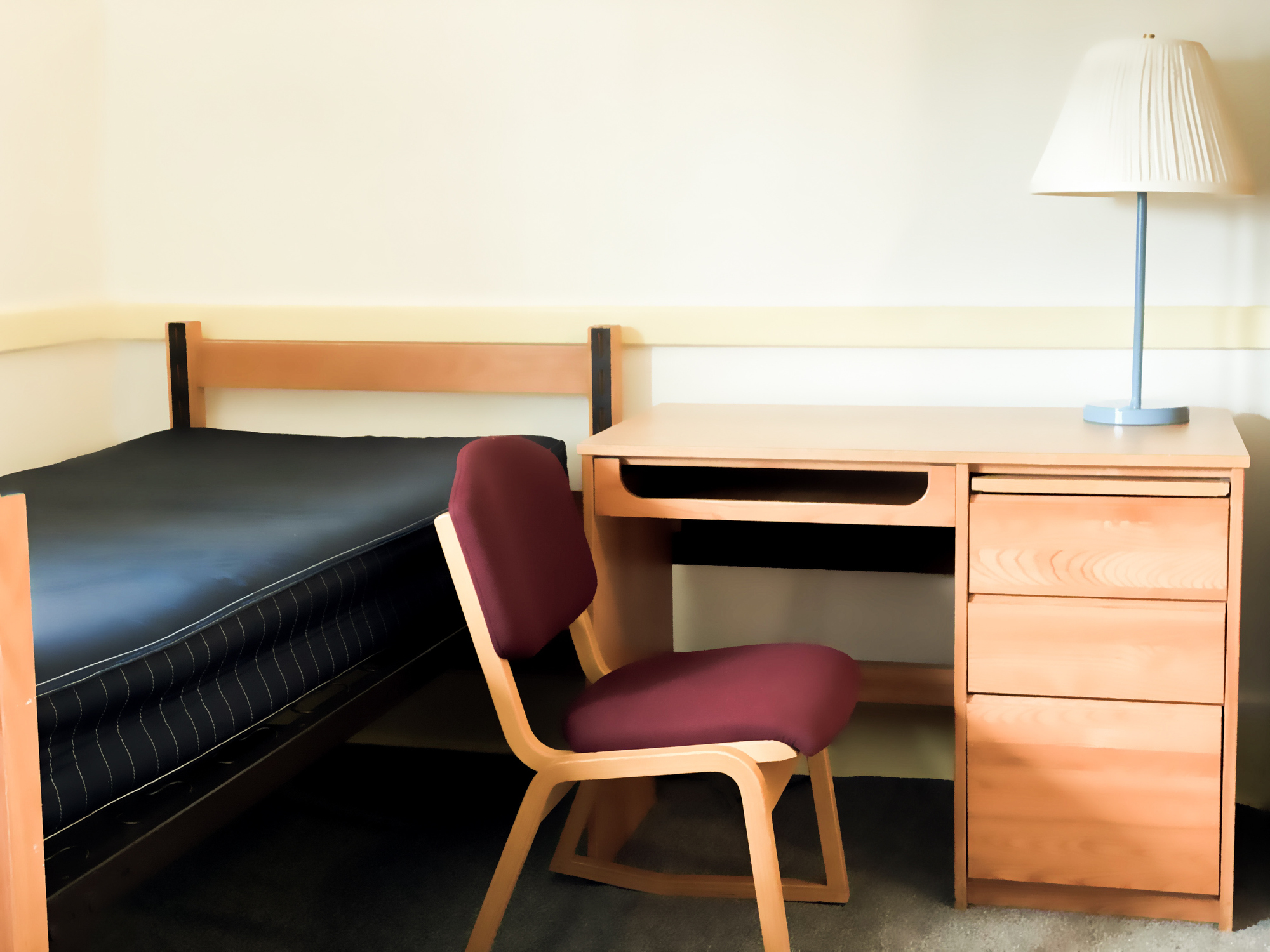 Empty student dormitory room with bed, desk, lamp, chair