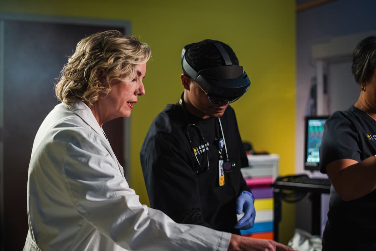 A student and a professor working with nursing simulation tech in a lab on campus