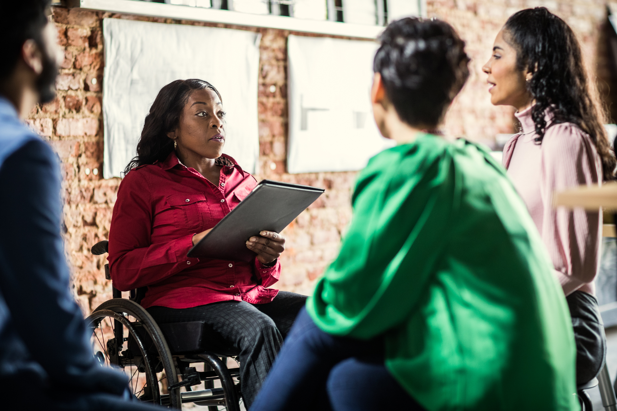 Black businesswoman in a wheelchair leads a brainstorm meeting with colleagues in the office.