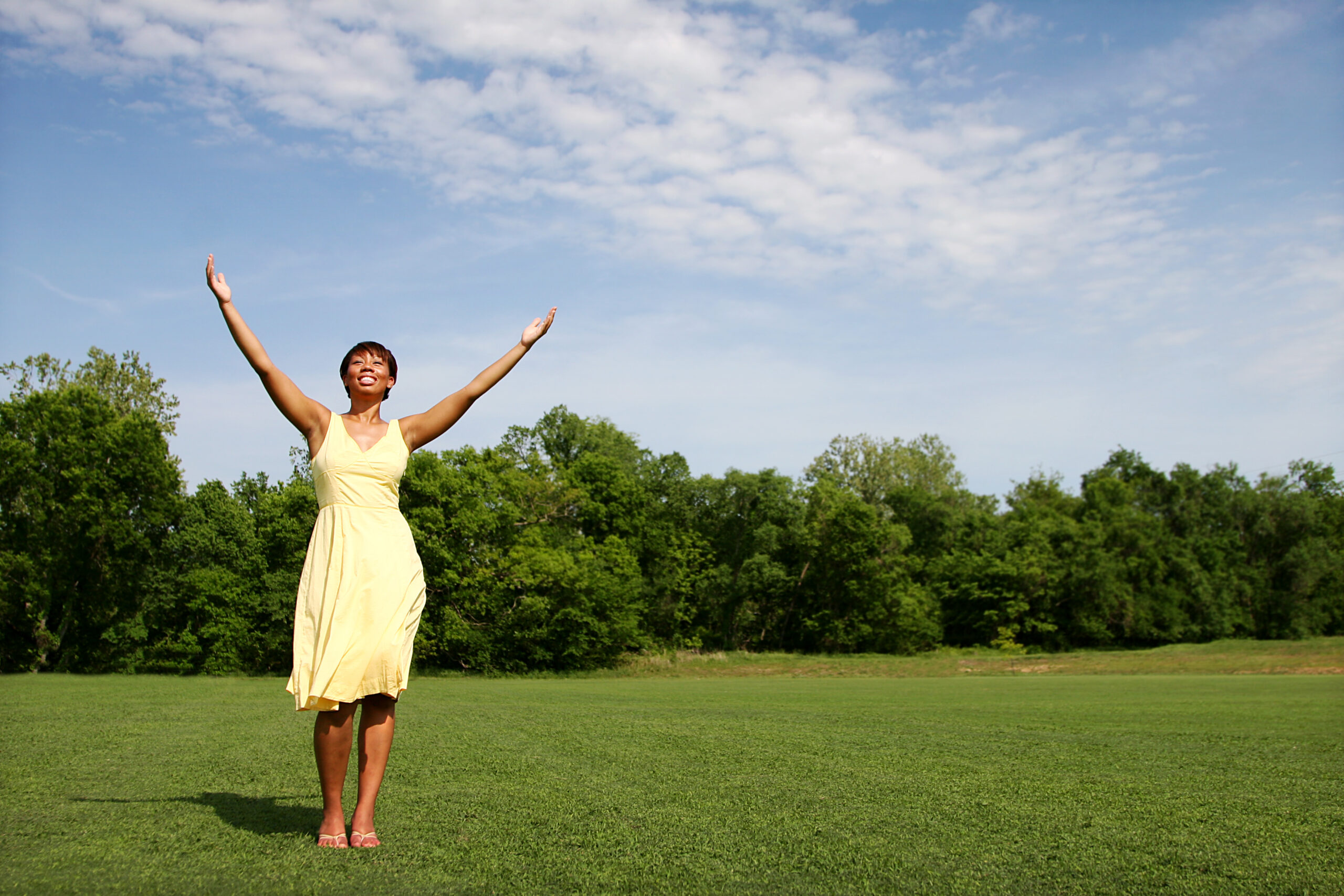 Young student enjoying sunshine, hands in the air