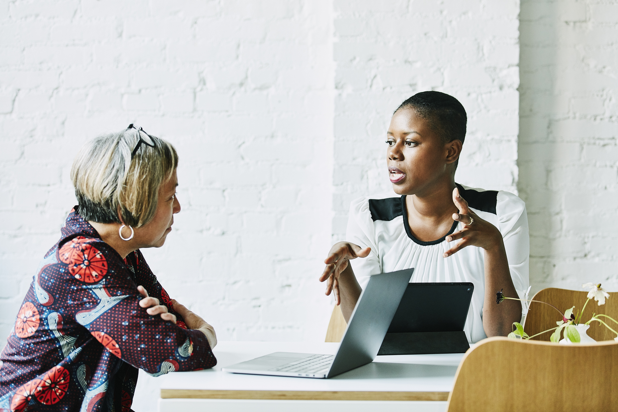 Two women talking to each other while looking at a laptop