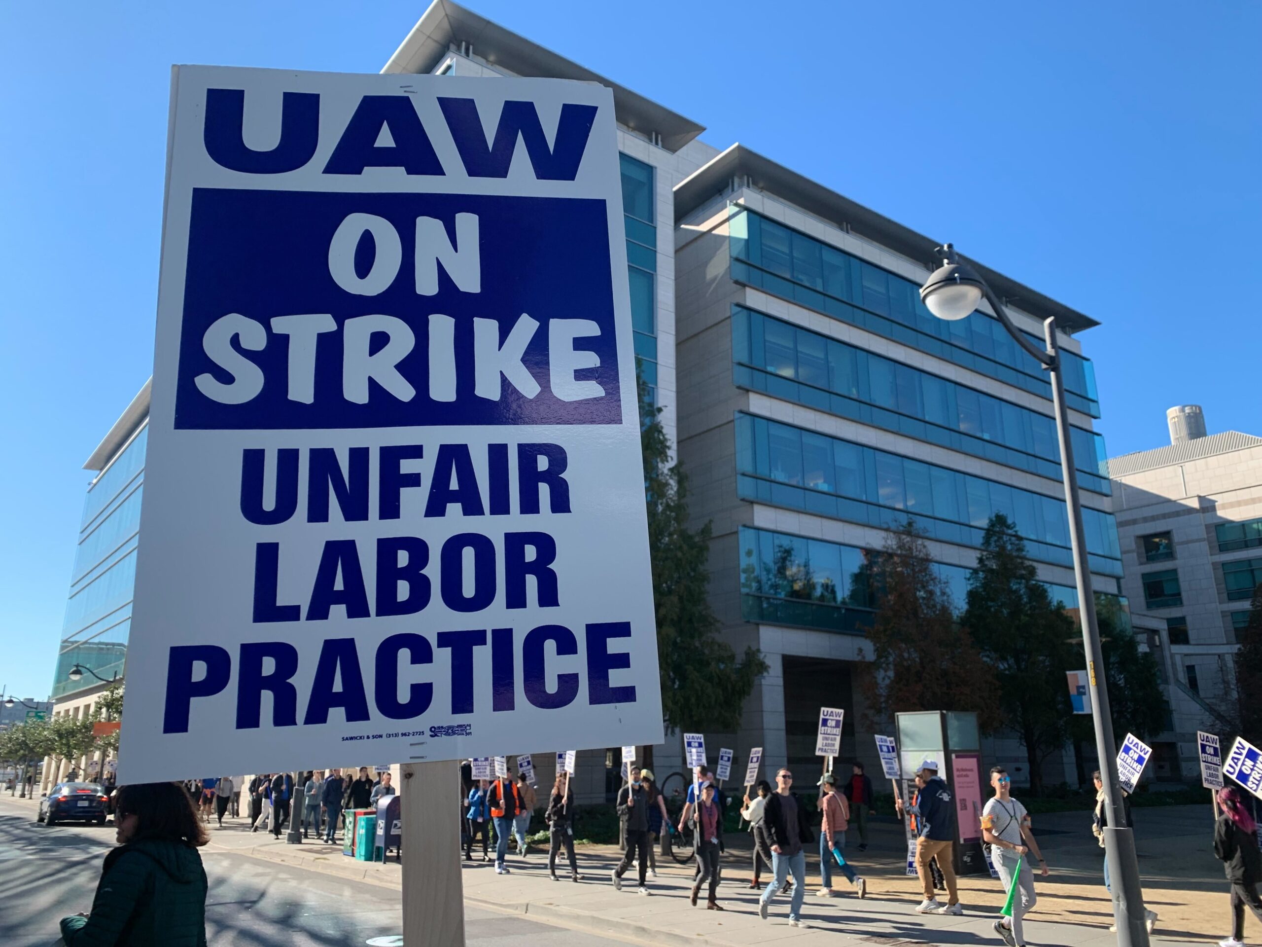 Academic workers hold signs and march at a strike in front of the University of California San Francisco campus administrative office to demand higher wages and more benefits for international students and working parents.