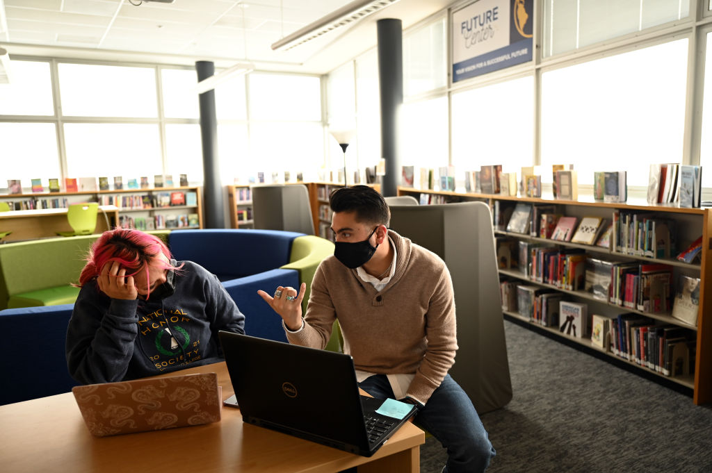 DENVER, CO - DECEMBER 9 : Derrek Sandoval, 32, right, helps Rosselyn Gurrola-Solis, 17, left, to apply scholarships at the library of Fred N. Thomas Career Education Center Early College in Denver, Colorado on Thursday, December 9, 2021.(Photo by Hyoung Chang/MediaNews Group/The Denver Post via Getty Images)