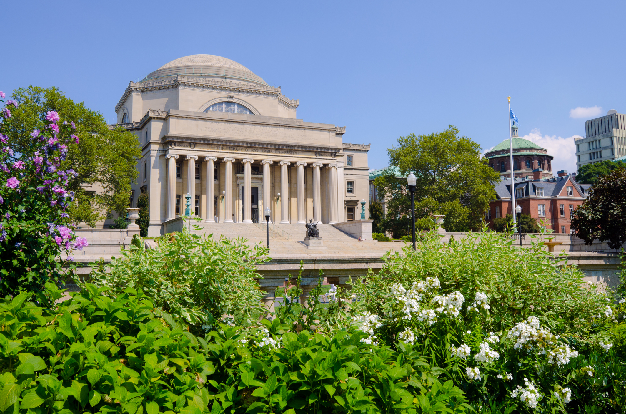 Low Memorial Library at Columbia University in New York City on a sunny spring day. The statue "Alma Mater," installed in 1904 and sculpted by Daniel Chester French, is located midway up the library steps.