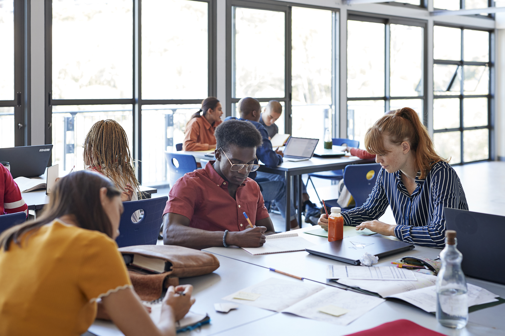 Young female and male university students studying while sitting on desk in classroom