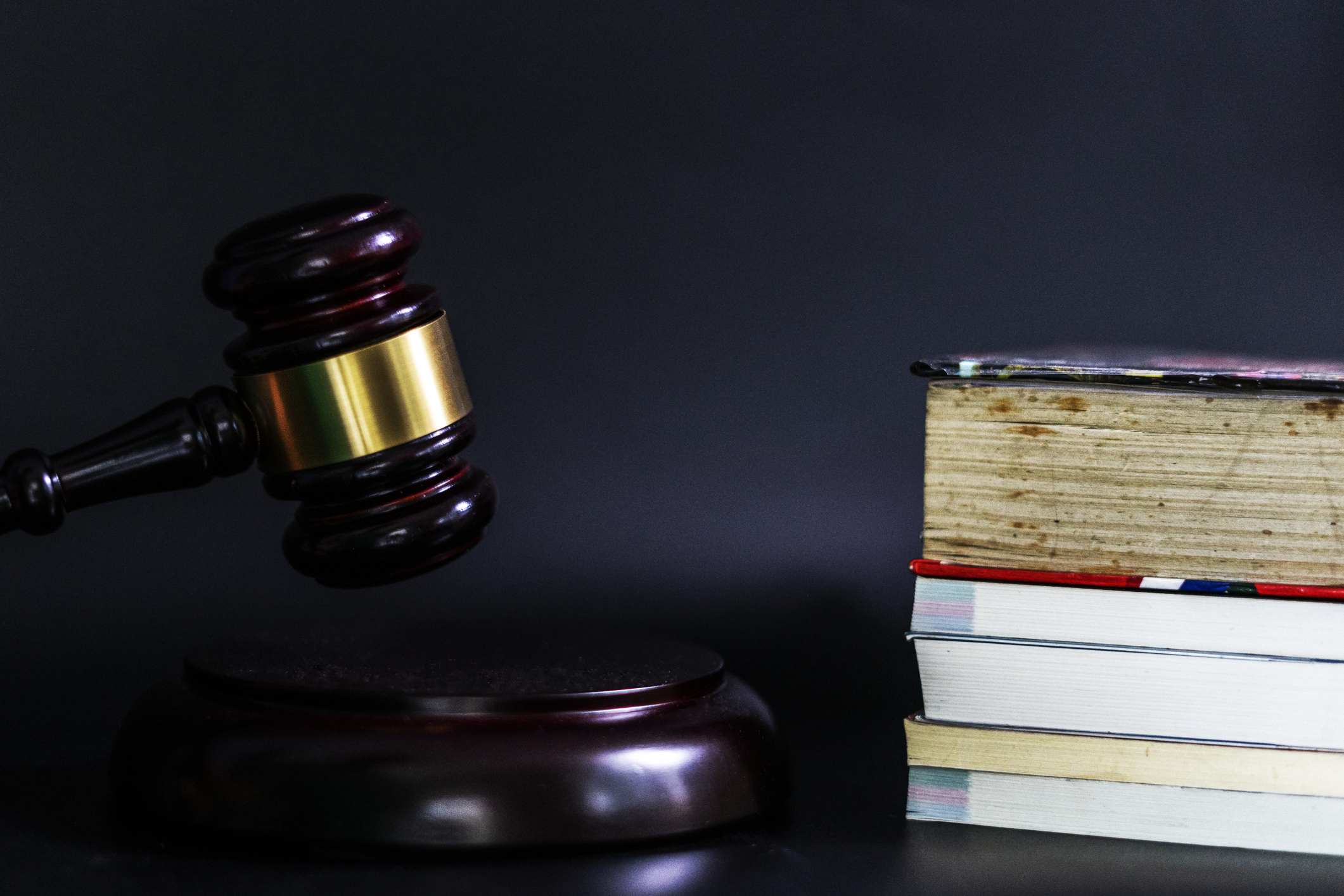 Law and Education concept. A picture of a gavel and a stack of books against a blank black background.