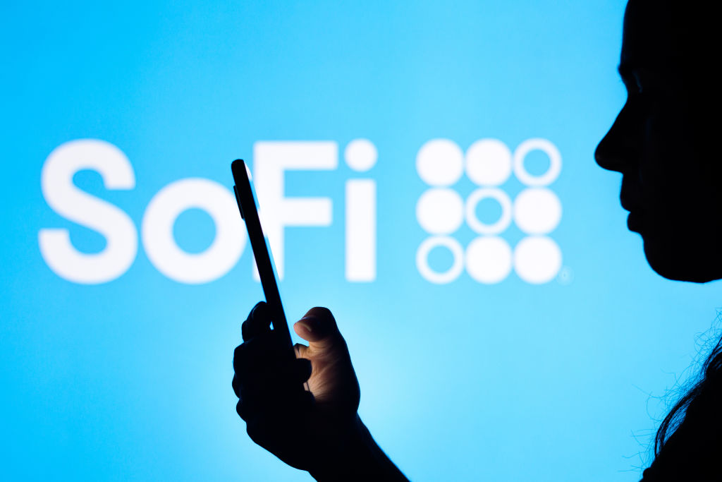 BRAZIL - 2022/04/12: In this photo illustration, a woman's silhouette holds a smartphone with the SoFi Technologies logo in the background. (Photo Illustration by Rafael Henrique/SOPA Images/LightRocket via Getty Images)