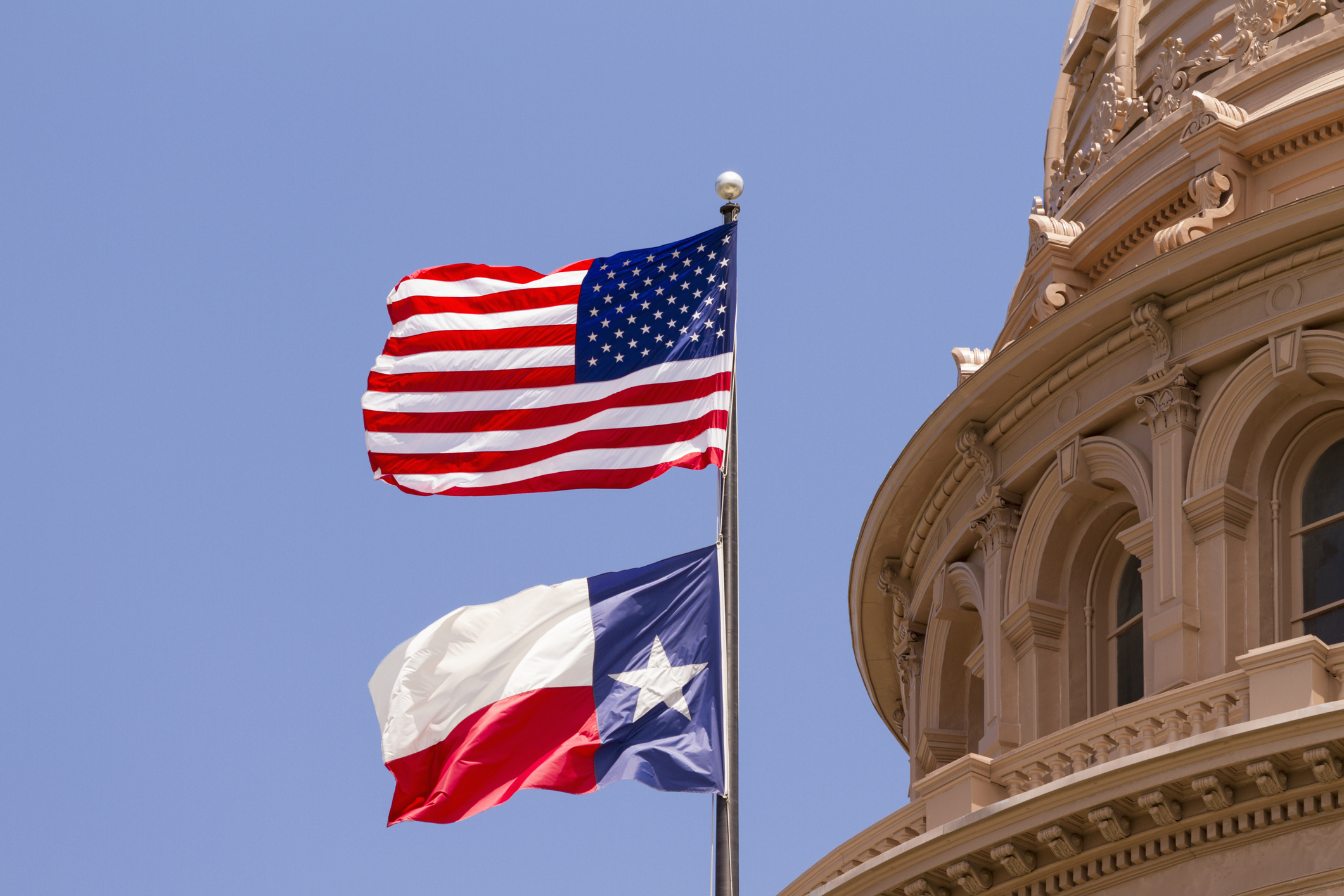 US and Texas flags flying over Texas State Capitol building, Austin, USA