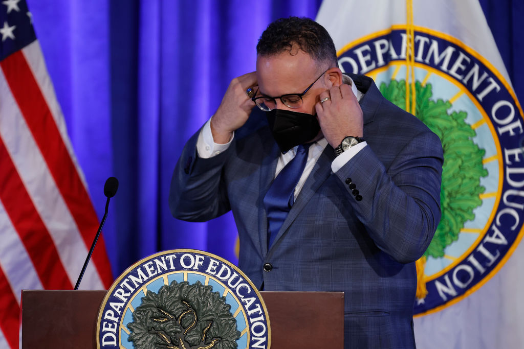 U.S. Education Secretary Miguel Cardona removes his face mask before delivering remarks at the department's Lyndon Baines Johnson Building in Washington, DC.