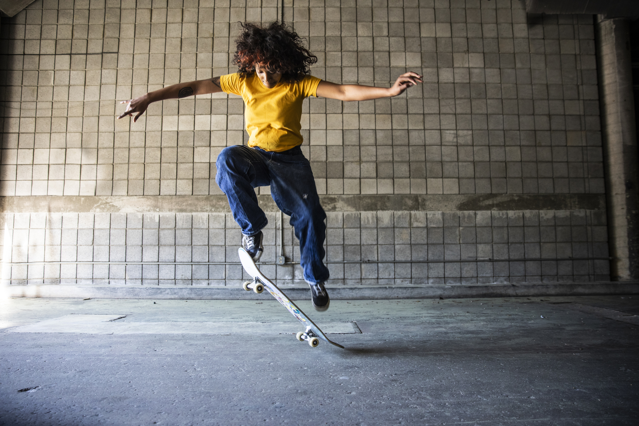 Female skateboarder performing jump in warehouse environment