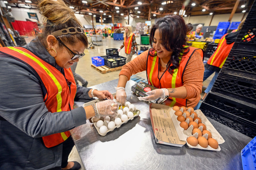 Volunteers Adriana Lira, left, and Angie Moran sort though eggs donated by Amazon Fresh at a grocery rescue station inside Second Harvest Food Bank