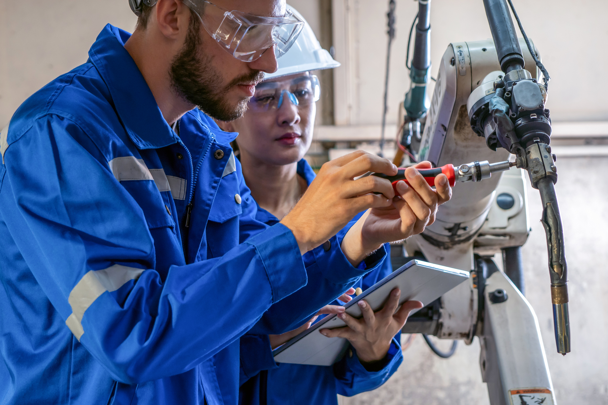 engineer repairing the robotic arm in a factory.