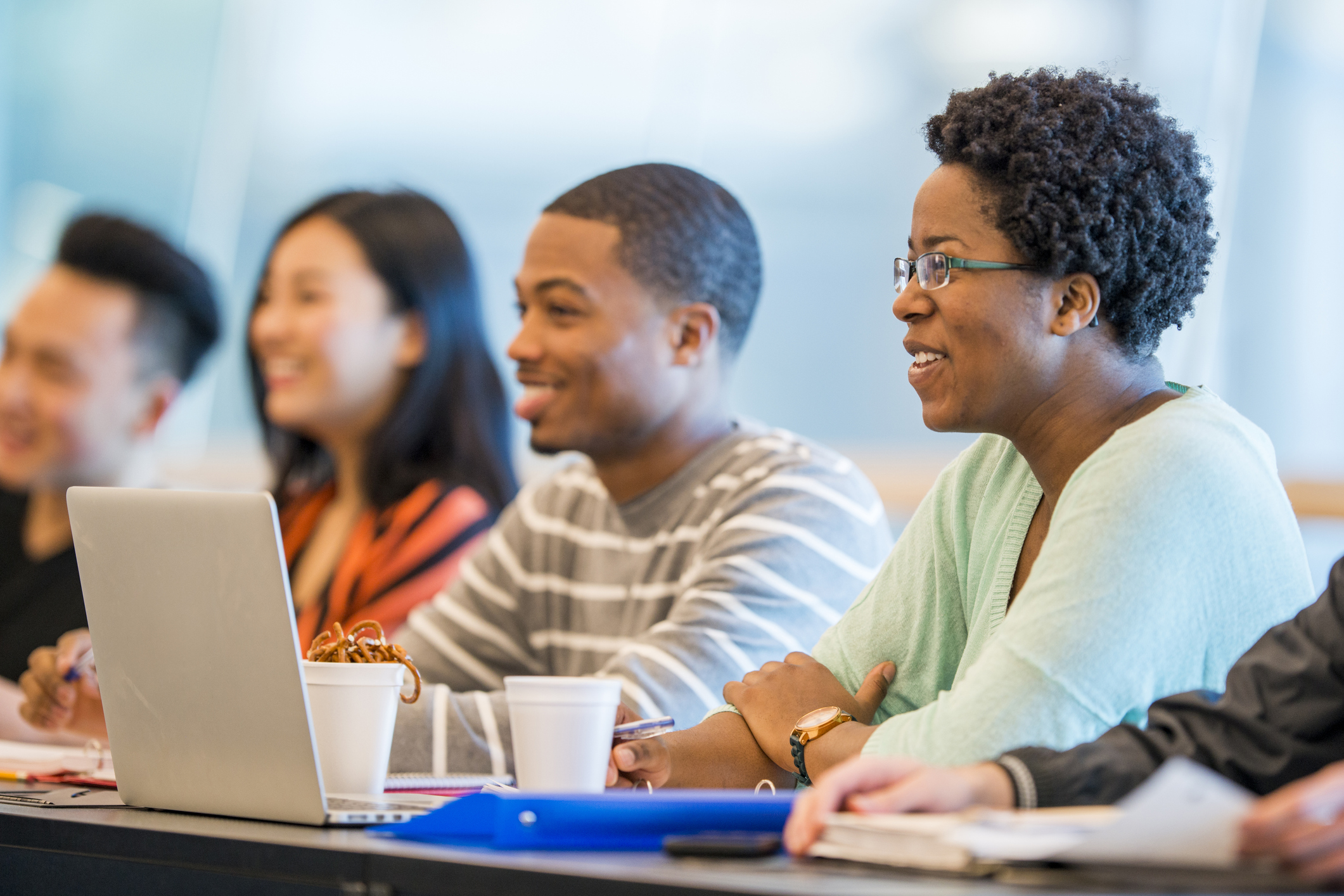 A multi-ethnic group of college students are sitting in a lecture hall and are working on a homework assignment for a group project.