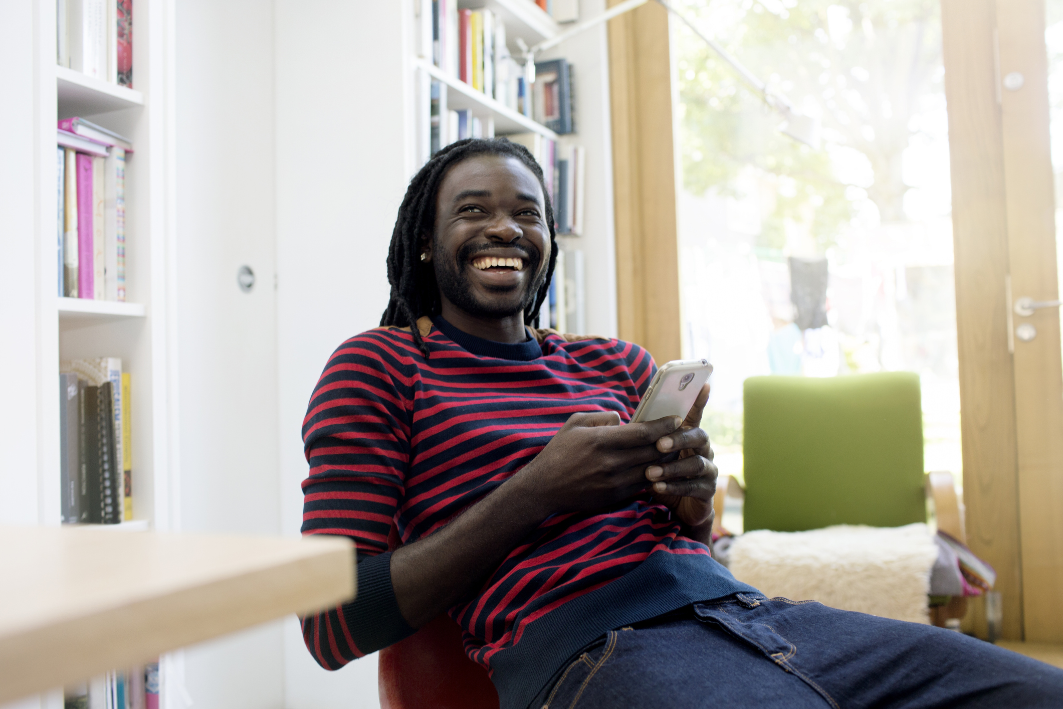 Student laughing while looking at his phone in the library