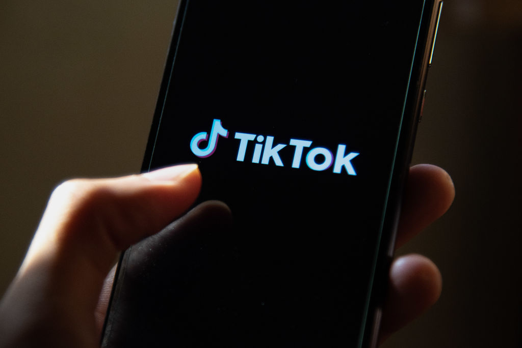 A college student opening the TikTok app on their smartphone.