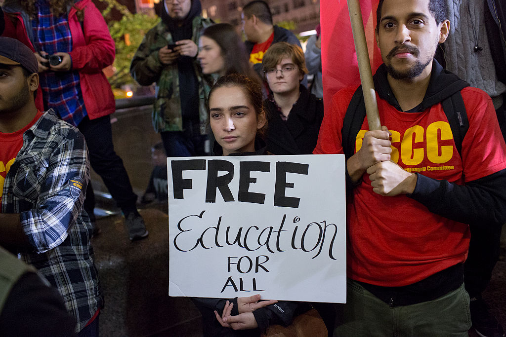 College students protesting, holding sign that reads "Free education for all"