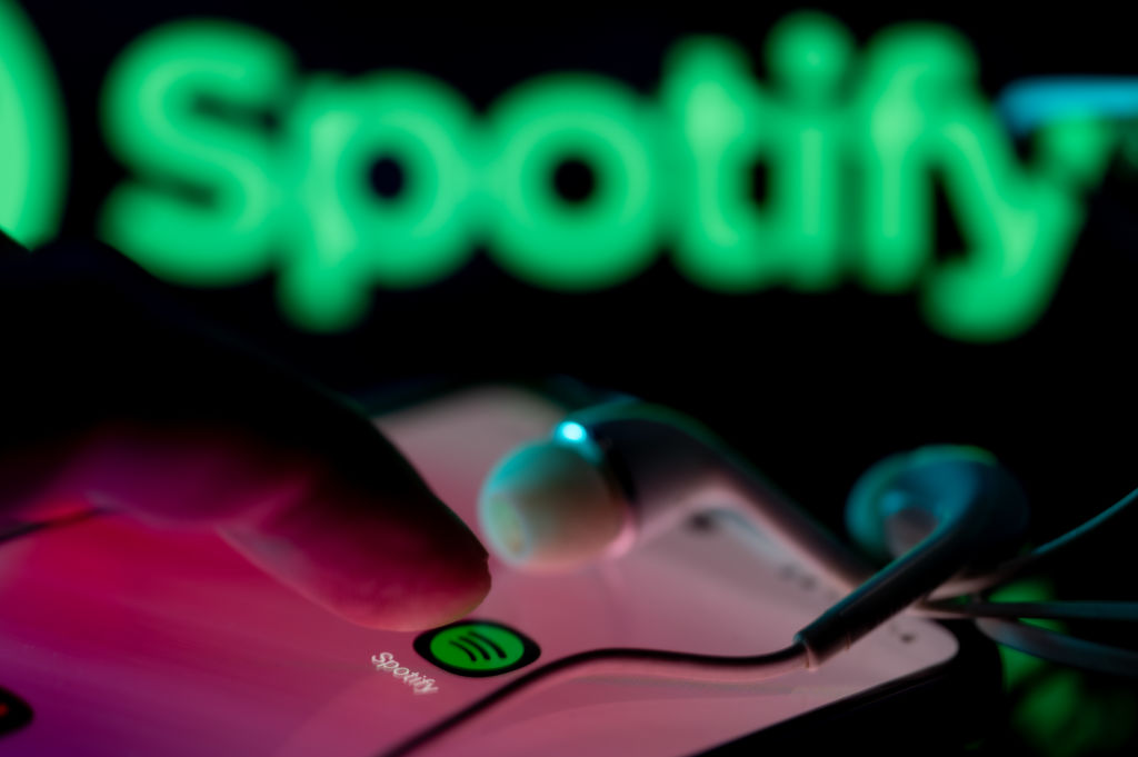 Person listening to Spotify app with Spotify logo in background