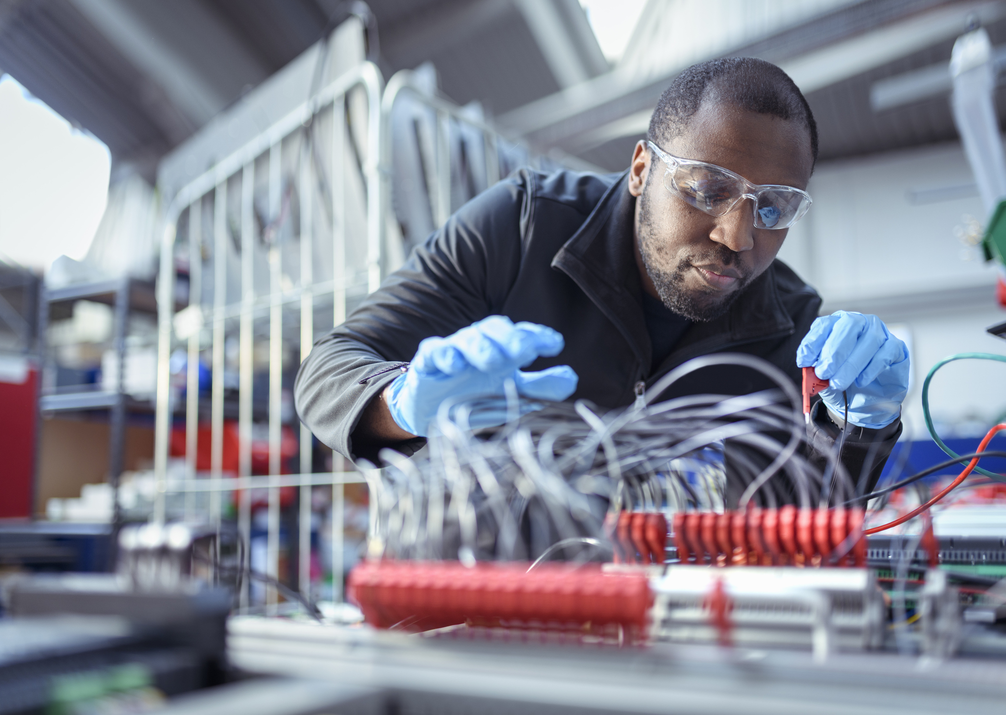 Black male electrical engineer assembling components in an electronics factory.