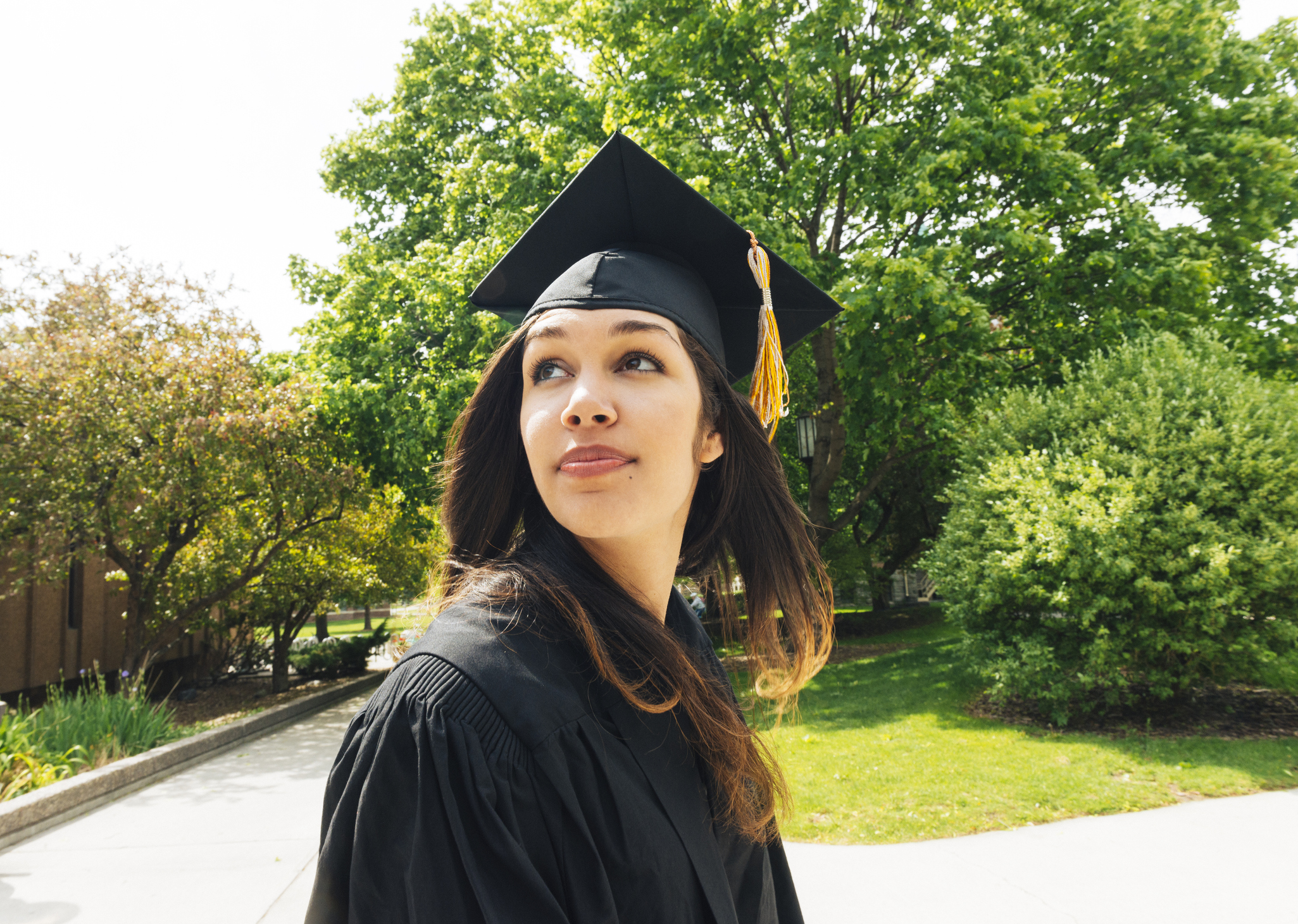 Latina college graduate looking back at the university as she celebrates her commencement.