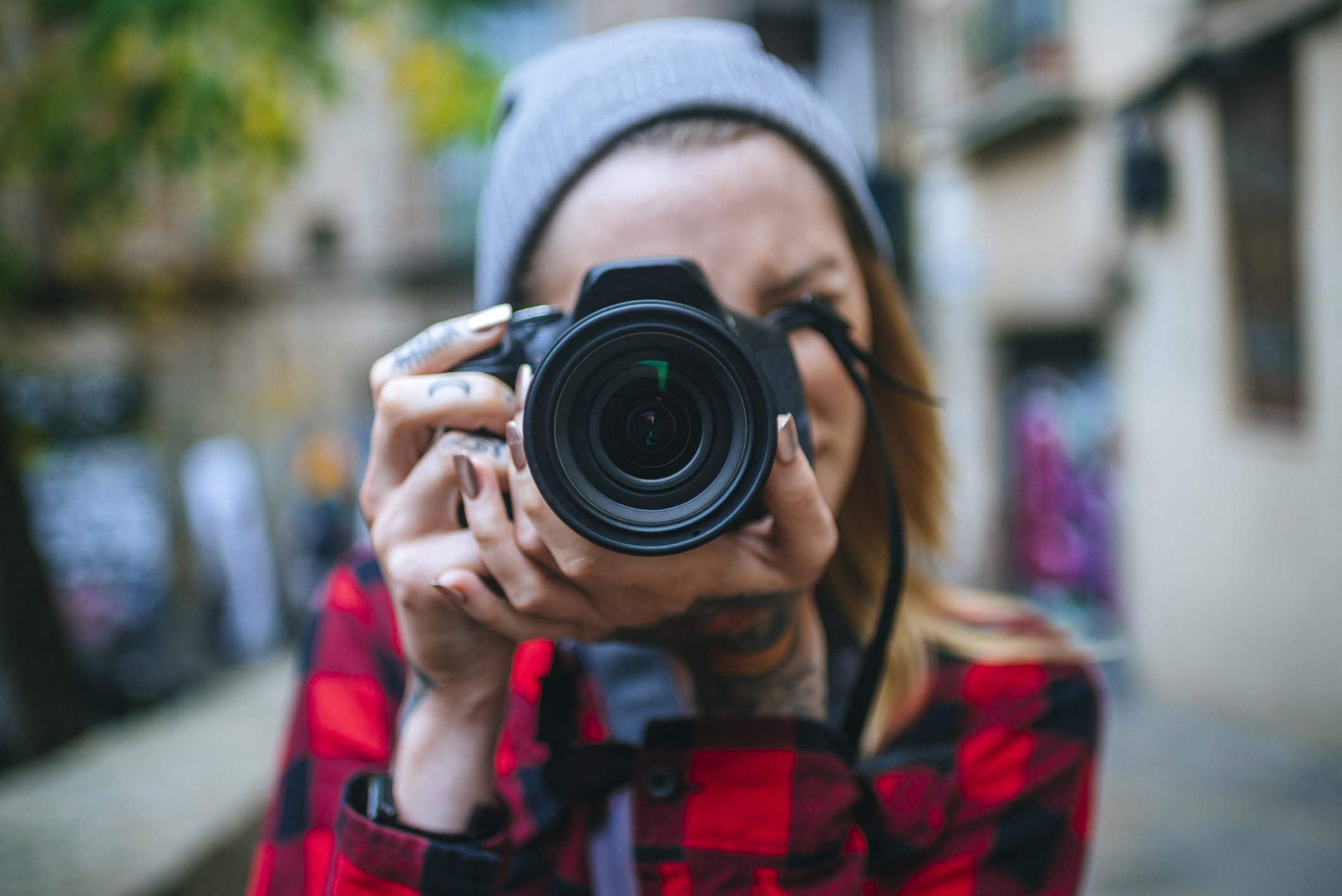 Female photographer taking a photo on a city street with a digital camera.