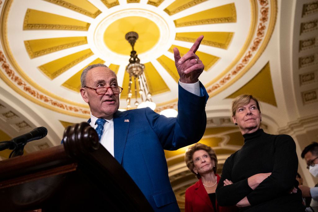 Senate Majority Leader Chuck Schumer speaking to reporters after a policy meeting with Senate Democrats at the U.S. Capitol in Washington, DC. Also pictured in the background are Senators Debbie Stabenow and Tammy Baldwin.